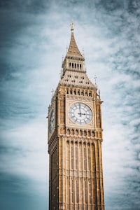 A tall clock tower with a cloudy sky in the background